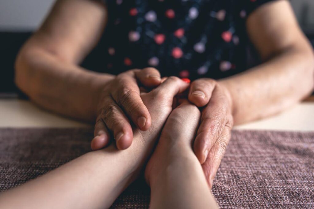 older female holding hands of younger female imparting our wisdom to the next generation